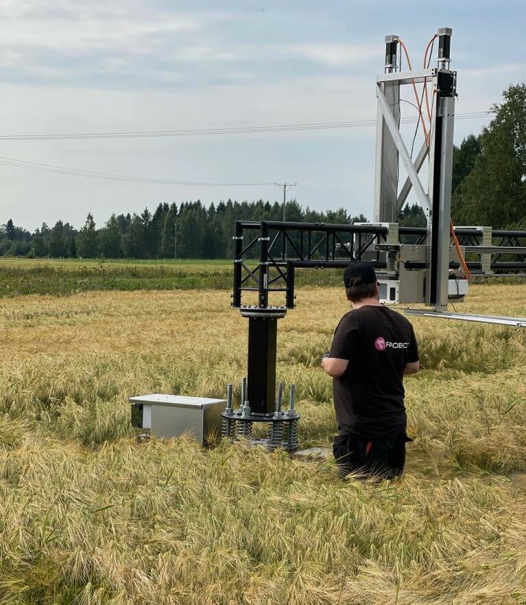 A man is standing next to a field robot in a field.