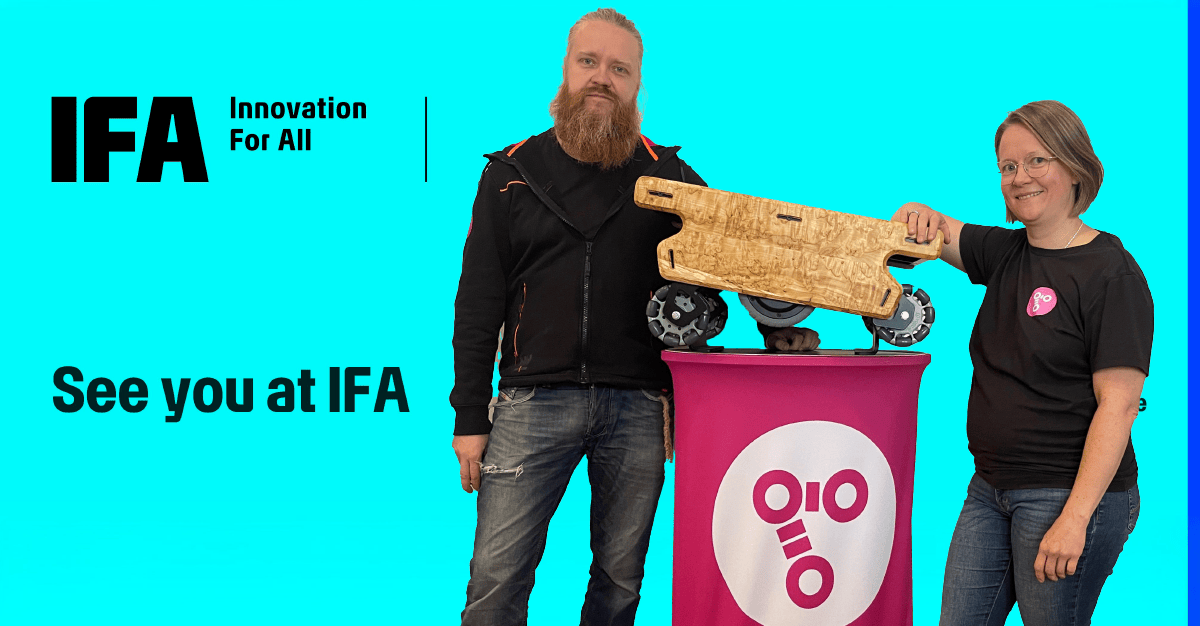 Two people showcasing an innovative mobile robot with a wooden casing. The mobile robot is placed on a table featuring the Probot logo. In the background, an advertisement for the IFA Berlin event.