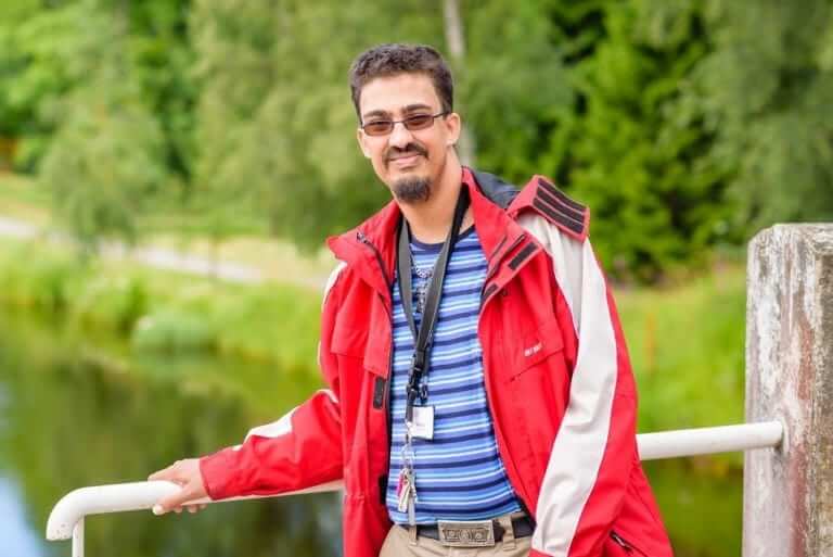 man smiling for the camera on the bridge.