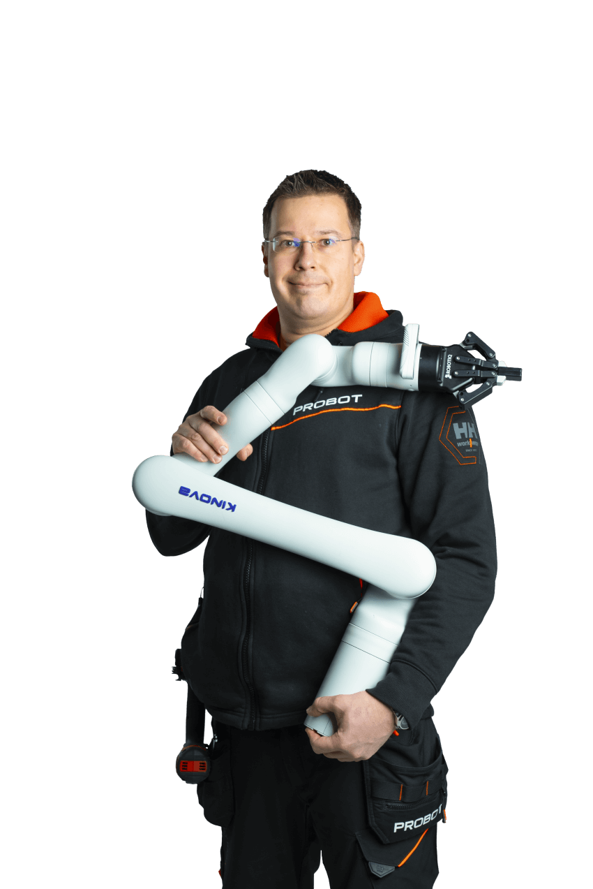 A man stands holding a robotic arm gripper and smiles at the camera.