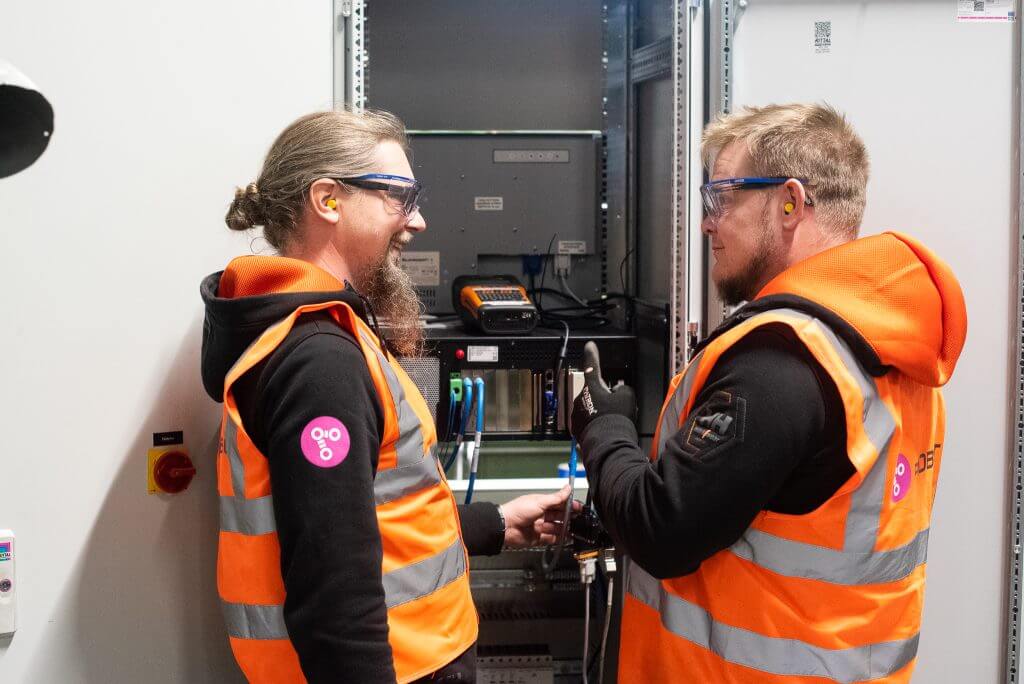 Two workers are happily working on the cables in the factory.