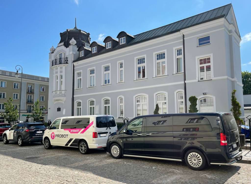 Three cars are parked in front of a beautiful building in Bialystok.