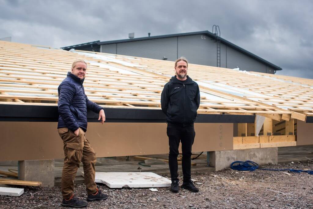 Two men standing in front of a new assembly hall under construction.