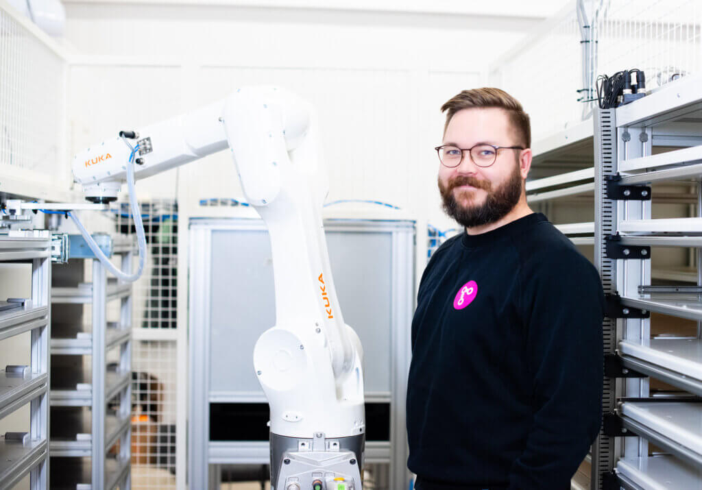 Our engineer Aleksi standing in the smart robot cell that minimizes waste