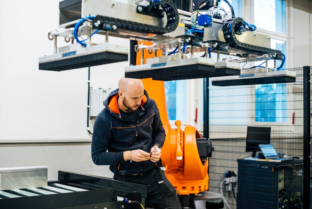 An employee is working on an industrial robot at a factory.