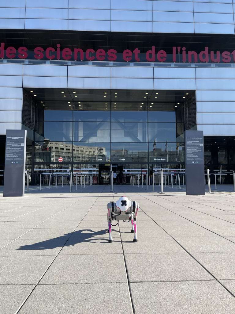 Robottikoira seisoo ranskan tiedekeskuksen pääovien edessä ulkona.