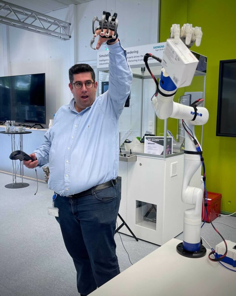 Henkilö kokeilemassa robotin ja sen tarttujan liikuttelua haprisen hanskan avulla.