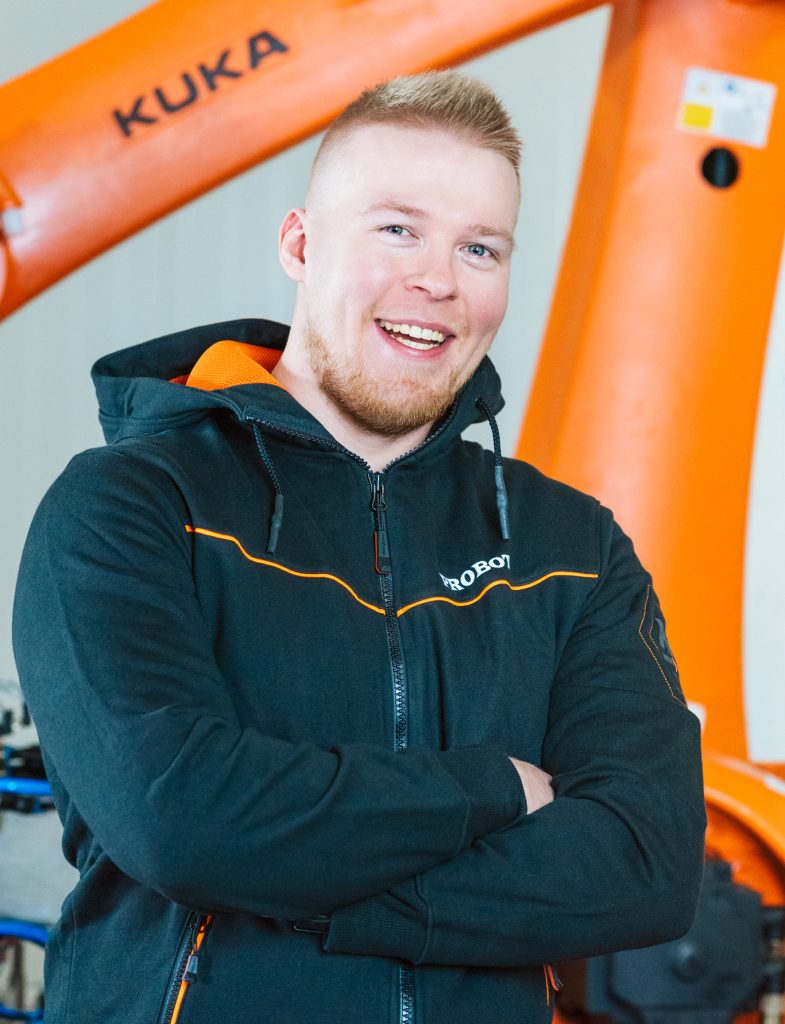 Man smiles in front of a robot.