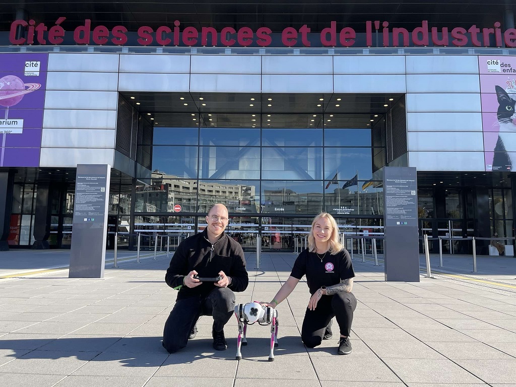 Kaksi Probot-tiimiläistä ja robottikoira Pariisin tiedekeskuksen edessä.