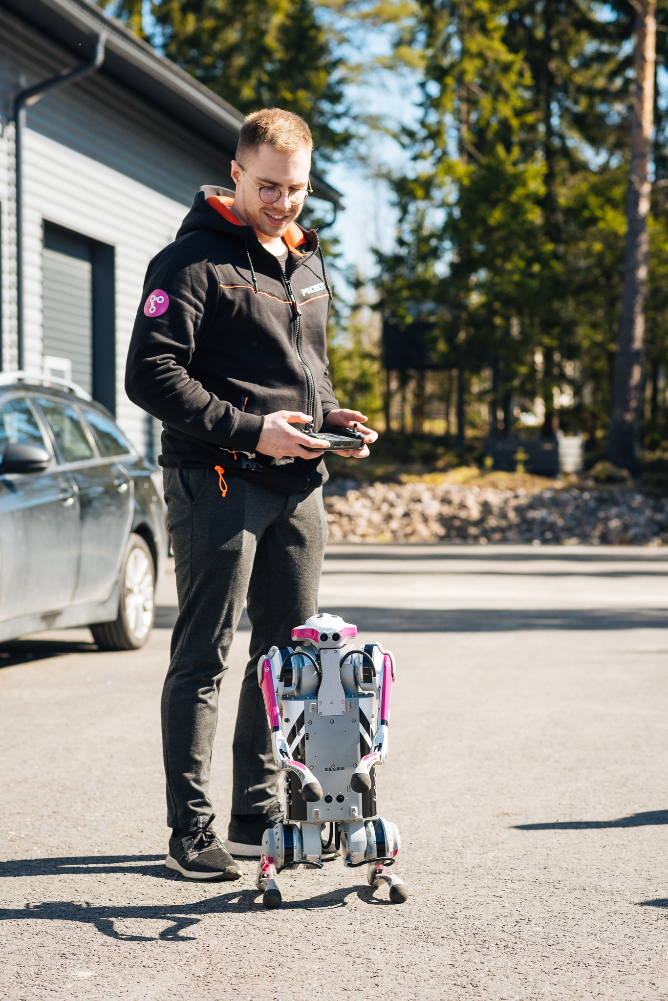 A man is standing outside with a robot dog, holding a controller in his hands.